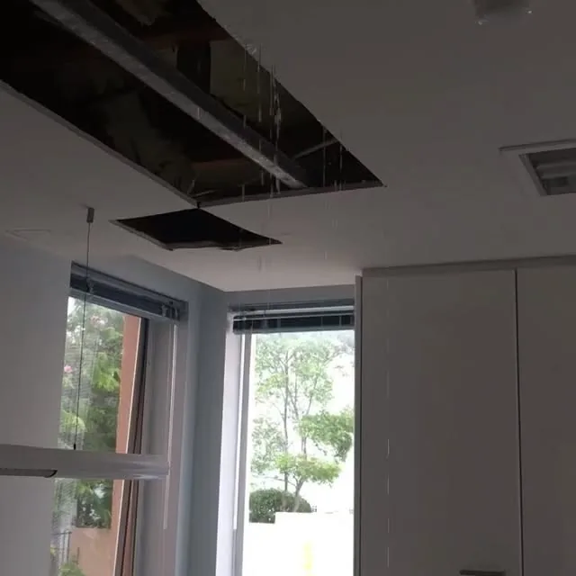Water leaking through an open ceiling access hatch in an office, a leak detection job