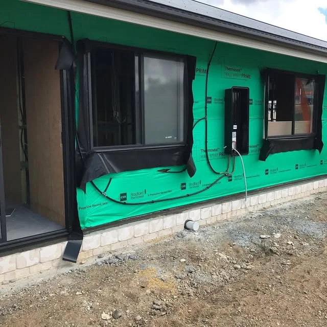 A new home under construction in green wrap, ready for plumbing fit-off